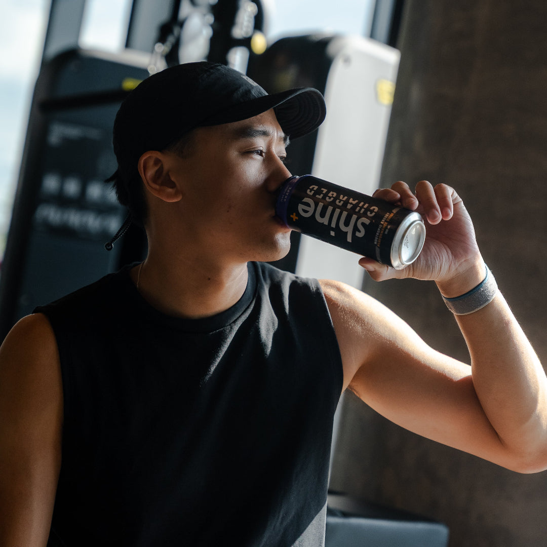 A focused athlete drinking Shine Charged mid-session in the gym